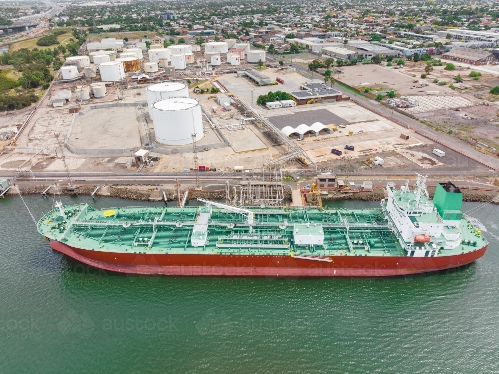 Aerial view of a large tanker at port near storage tanks - Australian Stock Image