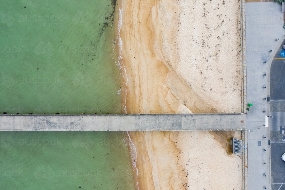 Aerial view of a long narrow jetty over a beach and clam water - Australian Stock Image