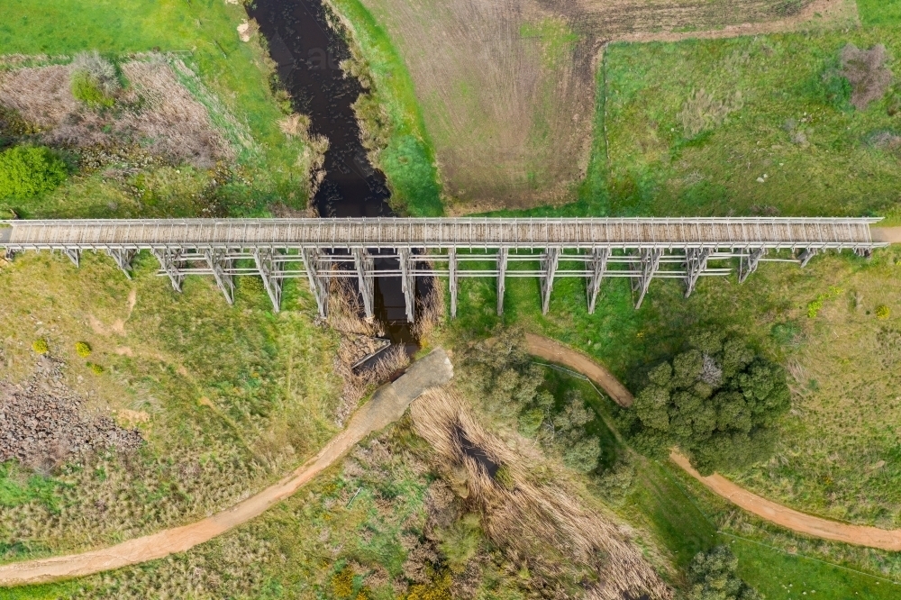 Aerial view of a long wooden trestle bridge across a green valley - Australian Stock Image