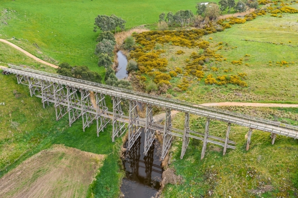 Aerial view of a long wooden trestle bridge across a green valley - Australian Stock Image