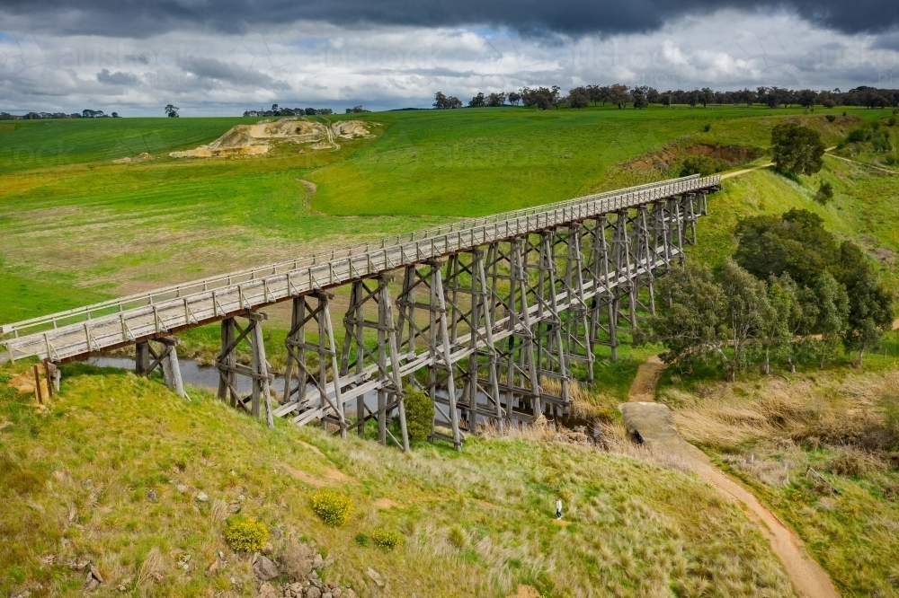 Aerial view of a long wooden trestle bridge across a green valley - Australian Stock Image