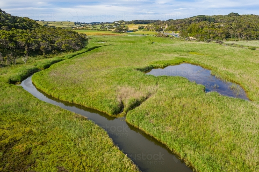 Image of Aerial view of a narrow creek winding through a valley of lush ...