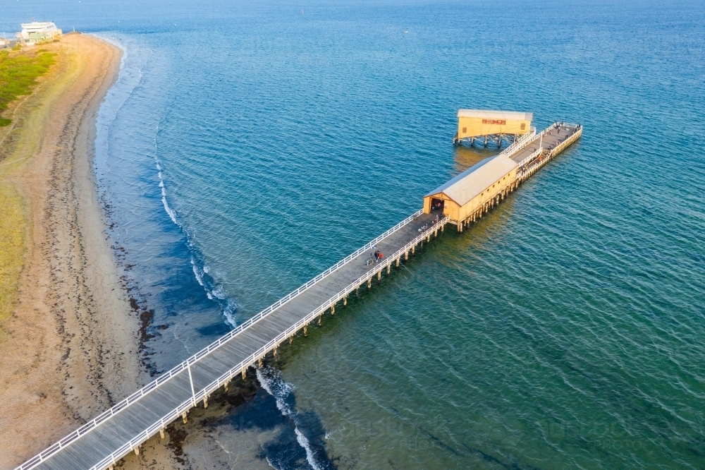 Aerial view of a narrow jetty off a beach going out over the ocean - Australian Stock Image