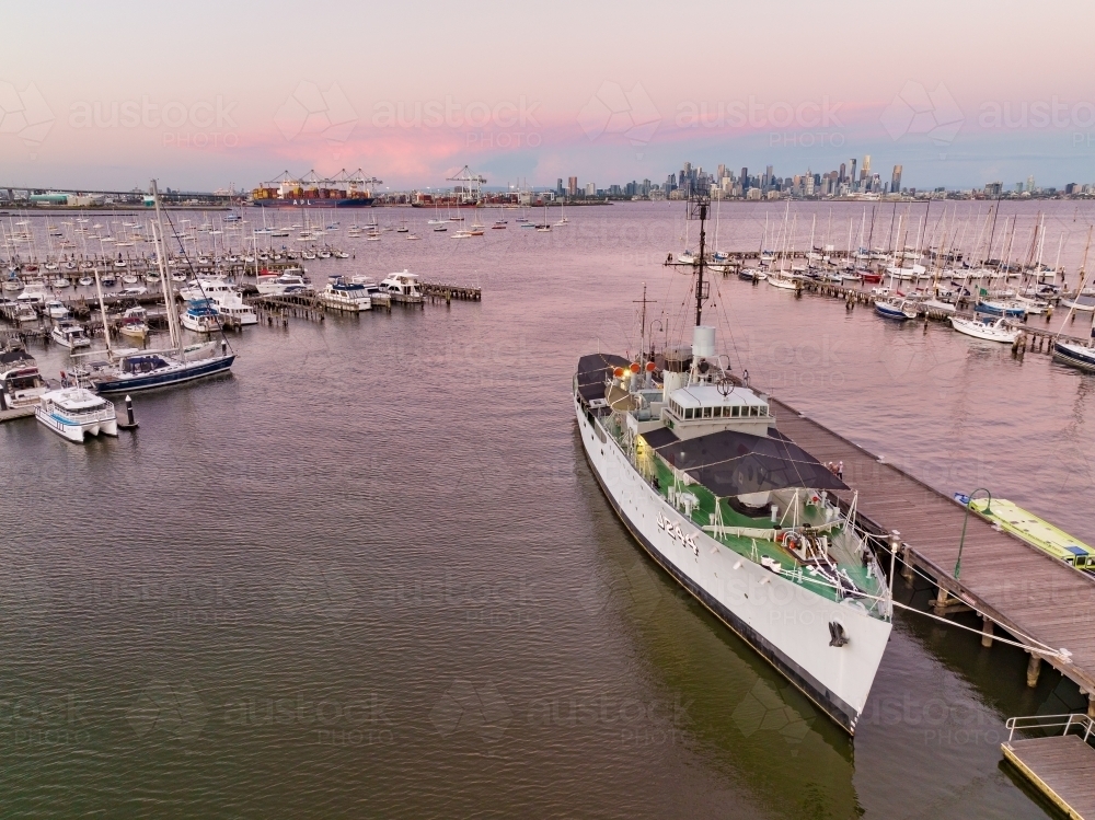 Aerial view of a navy ship docked at a pier surrounded by other boats and yachts - Australian Stock Image