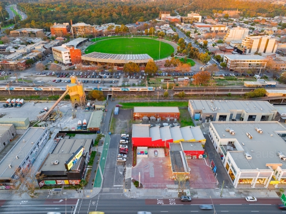 Aerial view of a railway line past a football stadium and commercial buildings - Australian Stock Image