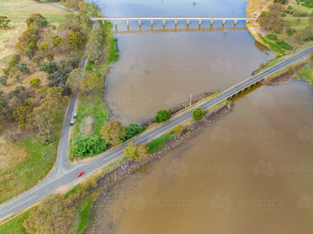 Aerial view of a railway viaduct and a road bridge crossing wide murky river - Australian Stock Image