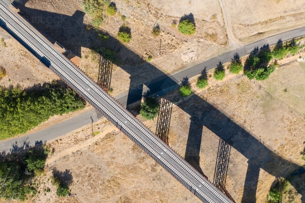 Aerial view of a railway viaduct and its shadow above a country road - Australian Stock Image