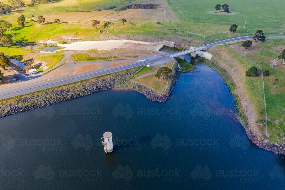 Aerial view of a reservoir with a water tower and a road crossing a spillway - Australian Stock Image