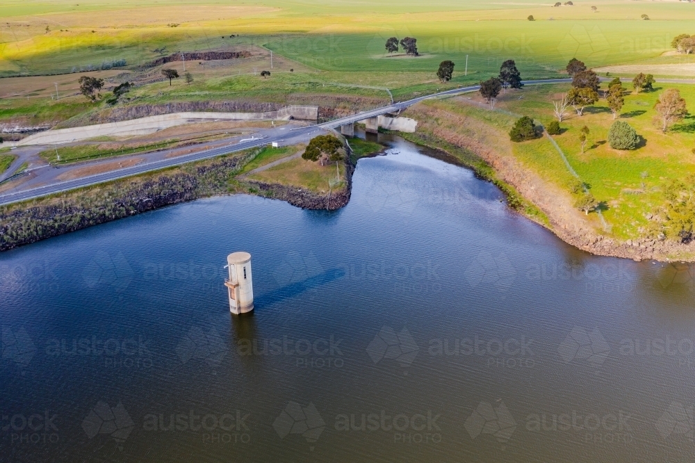 Aerial view of a reservoir with a water tower and a road crossing a spillway - Australian Stock Image