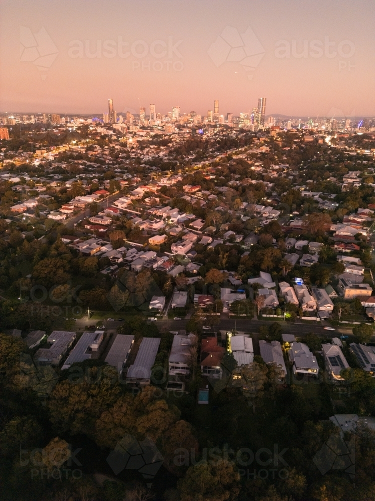 Aerial view of a residential area under the sunset sky with city skyline at the edge - Australian Stock Image