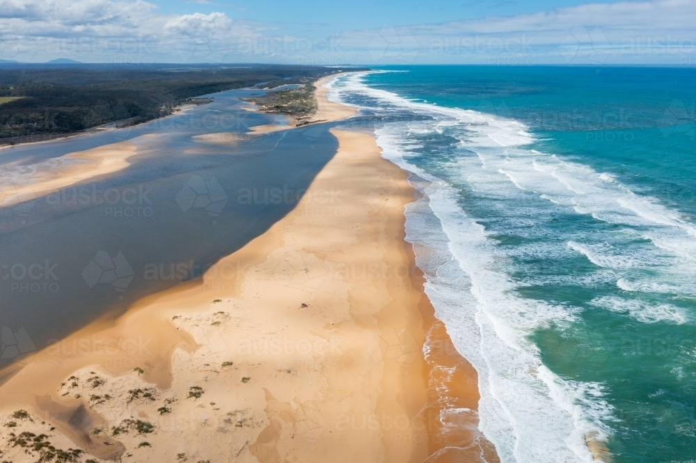 Aerial view of a river flowing out to sea through a sandy beach - Australian Stock Image