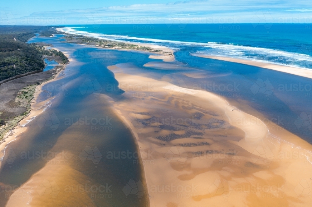 Aerial view of a river running next to a sandy beach then out to sea - Australian Stock Image