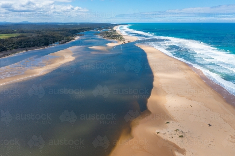 Aerial view of a river running next to a sandy beach then out to sea - Australian Stock Image