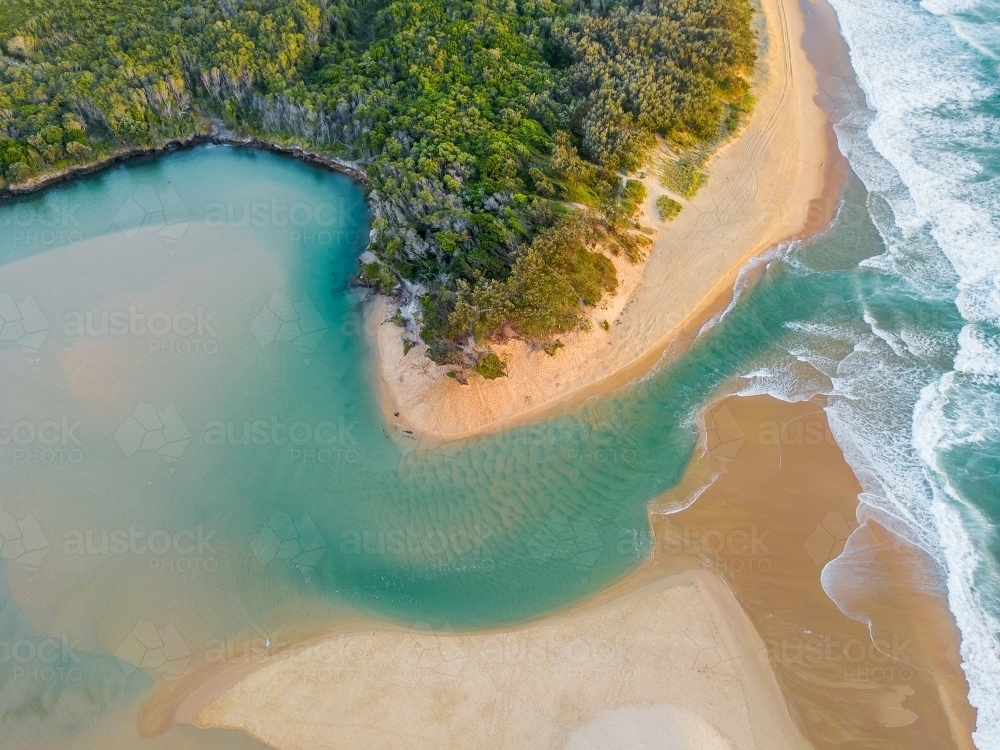 Aerial view of a river winding through a beach and out to sea - Australian Stock Image