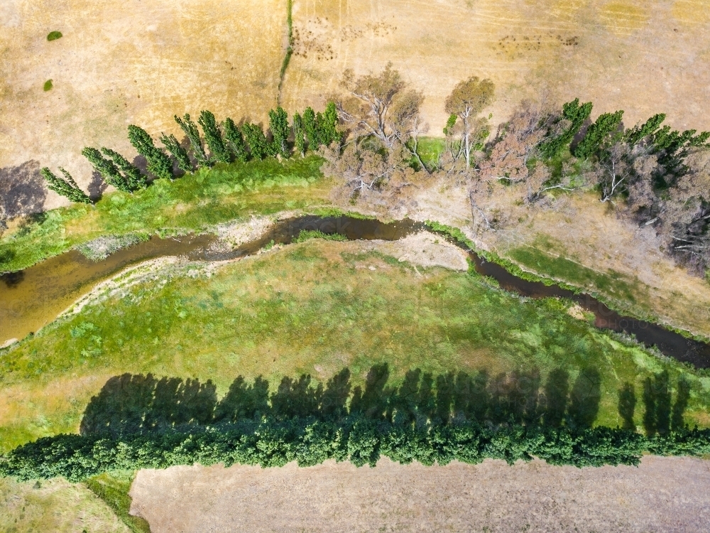 Aerial view of a river with green grass and trees lining its banks - Australian Stock Image