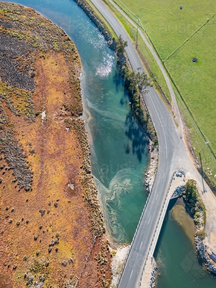 Aerial view of a road alongside a river and crossing over a bridge - Australian Stock Image