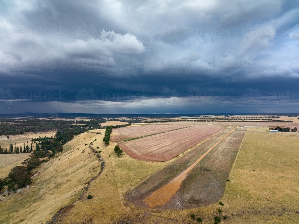 Aerial view of a rural airstrip under heavy dark clouds - Australian Stock Image