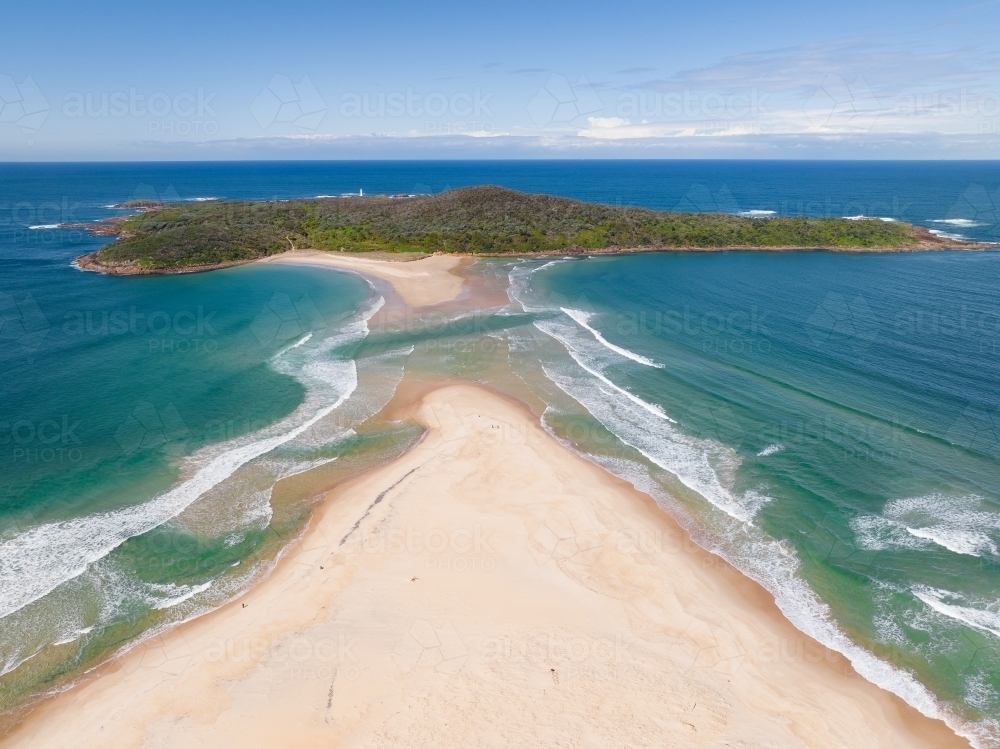 Image of Aerial view of a sand spit leading out to a forested coastal ...