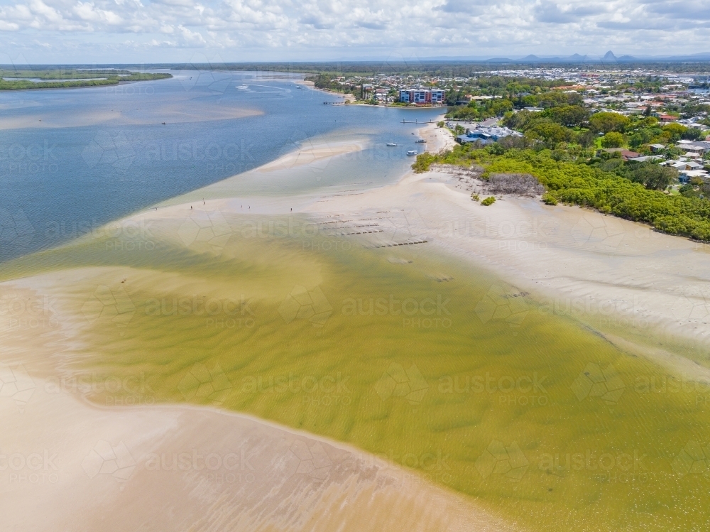 Aerial view of a shallow inlet flowing out to sea over sand bars - Australian Stock Image