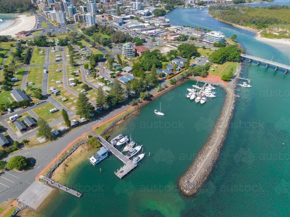 Aerial view of a sheltered marina on a coastal river alongside a city caravan park - Australian Stock Image