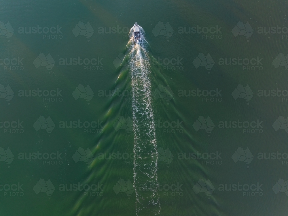 Aerial view of a small boat creating a wake in a wide river - Australian Stock Image