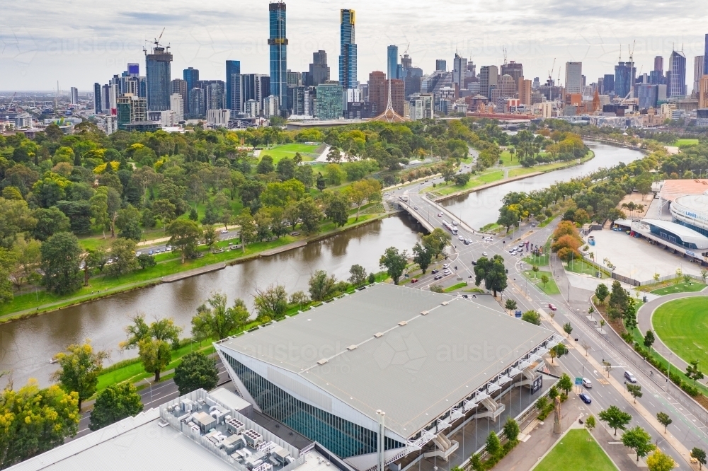 Aerial view of a sports stadium next to a river with a city skyline behind. - Australian Stock Image