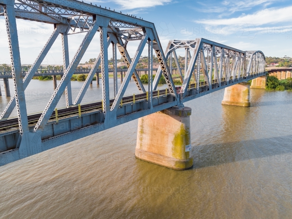 Aerial view of a steel span bridge crossing a wide brown river - Australian Stock Image