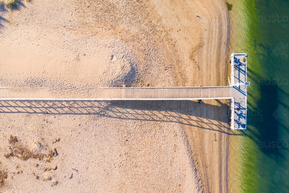 Aerial view of a T shaped jetty over a beach to the shoreline - Australian Stock Image