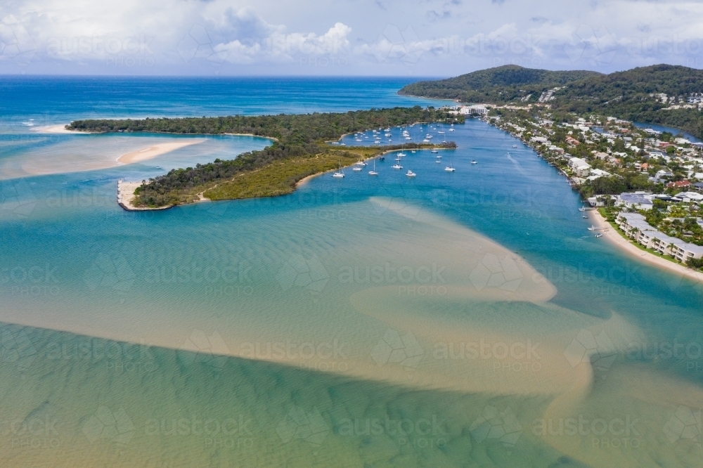 Aerial view of a wide blue river flowing past a coastal town and out to sea - Australian Stock Image