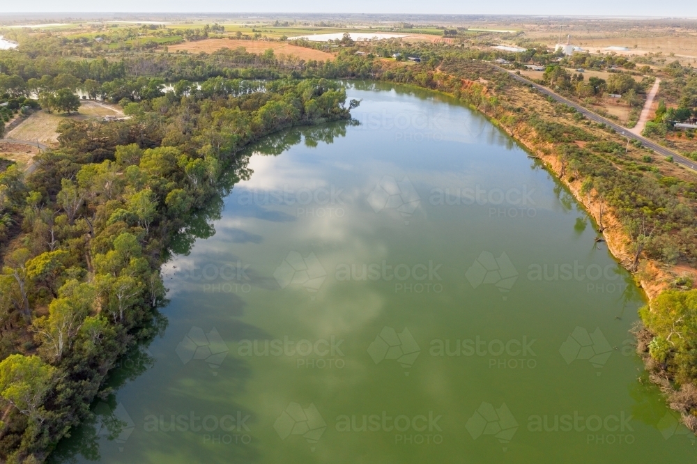 Aerial view of a wide murky river with gum trees along the banks - Australian Stock Image