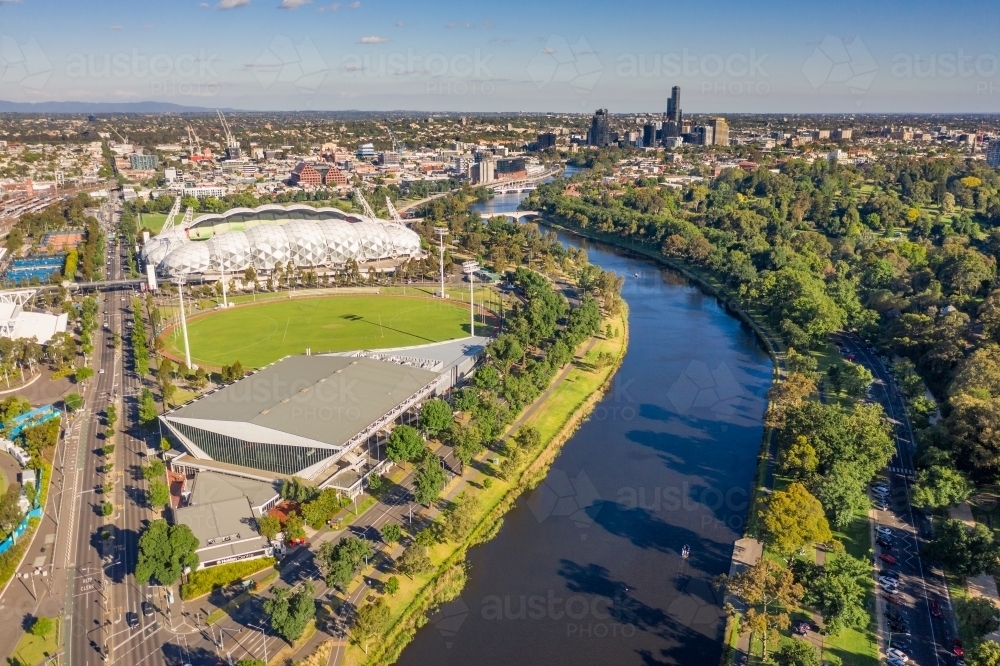 Aerial view of a wide river winding through a city with parkland and sporting facilities along side - Australian Stock Image