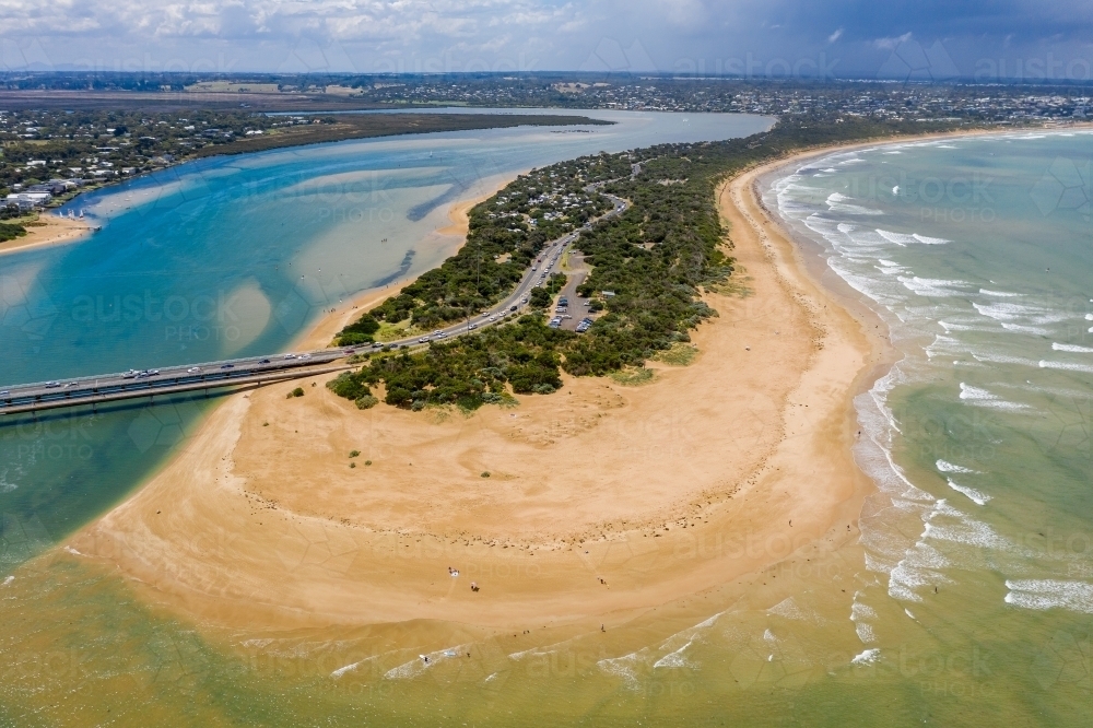 Aerial view of a wide sandy beach around a narrow strip of land between a river and the ocean - Australian Stock Image