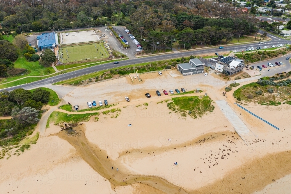 Aerial view of a wide sandy beach with a carpark above and bowling green behind - Australian Stock Image