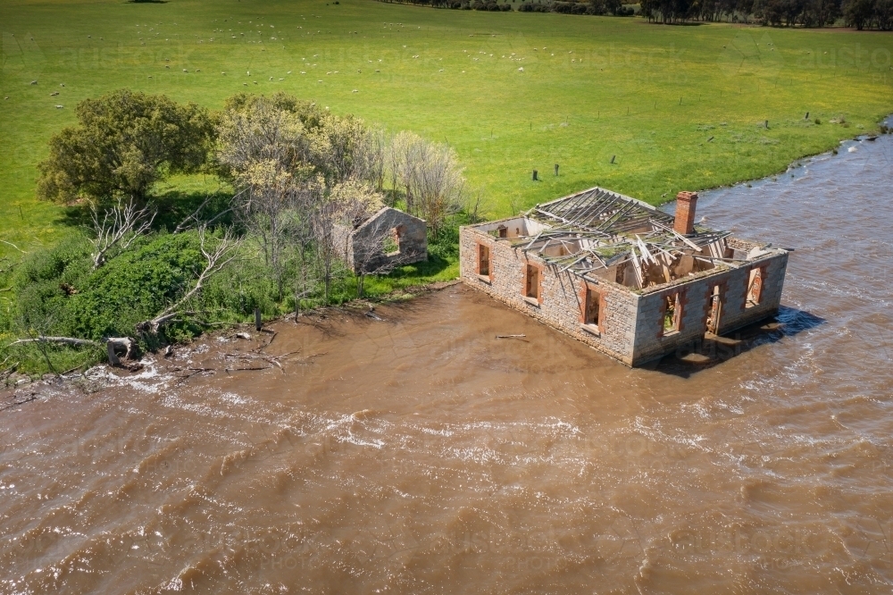 Aerial view of an abandoned historic farm house full of water on the edge of a lake - Australian Stock Image