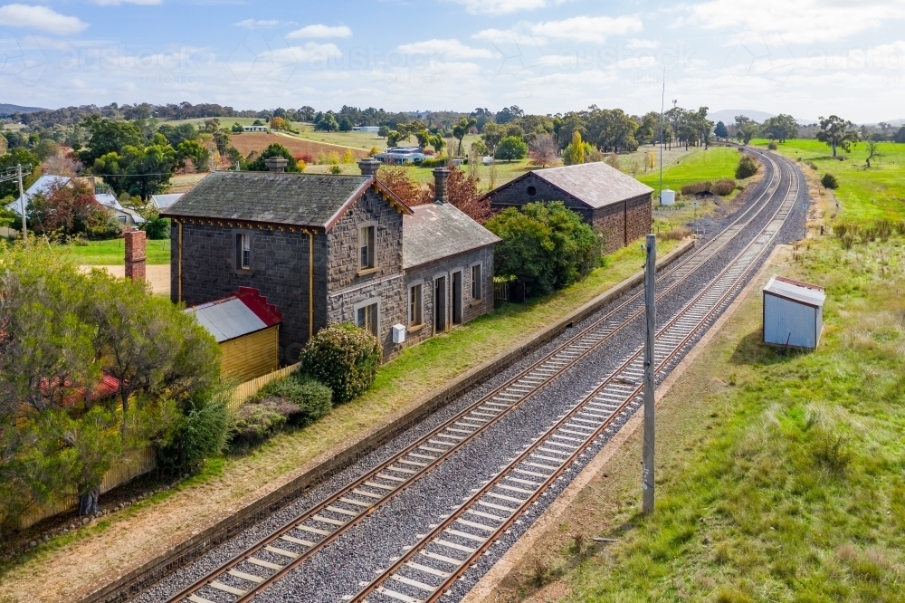 Aerial view of an deserted blue stone railway station with grass growing on the platform - Australian Stock Image