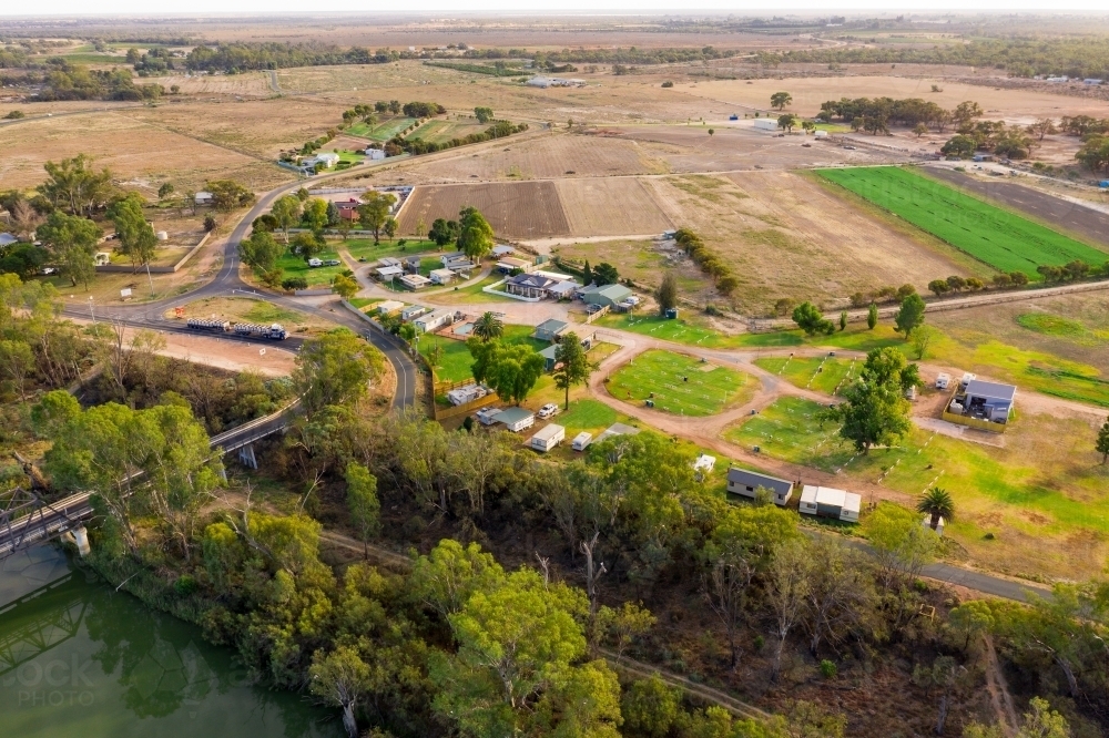 Aerial view of an empty caravan park on the banks of a river surrounded by orchards - Australian Stock Image