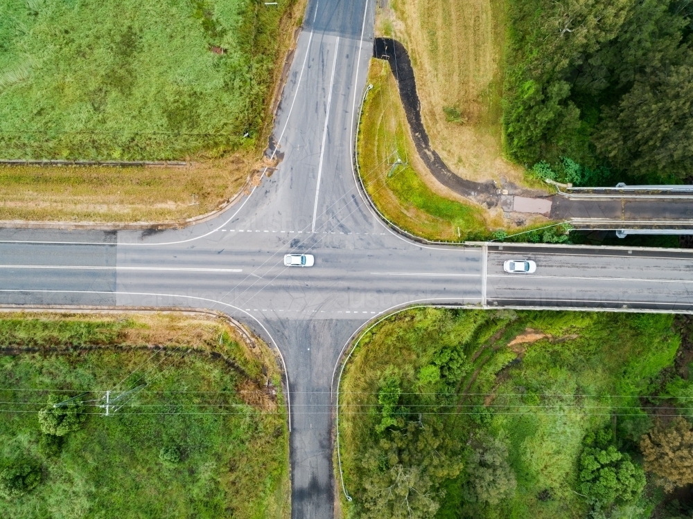 Aerial view of an open rural crossroads bordered by paddocks and hunter river with bridge over it - Australian Stock Image