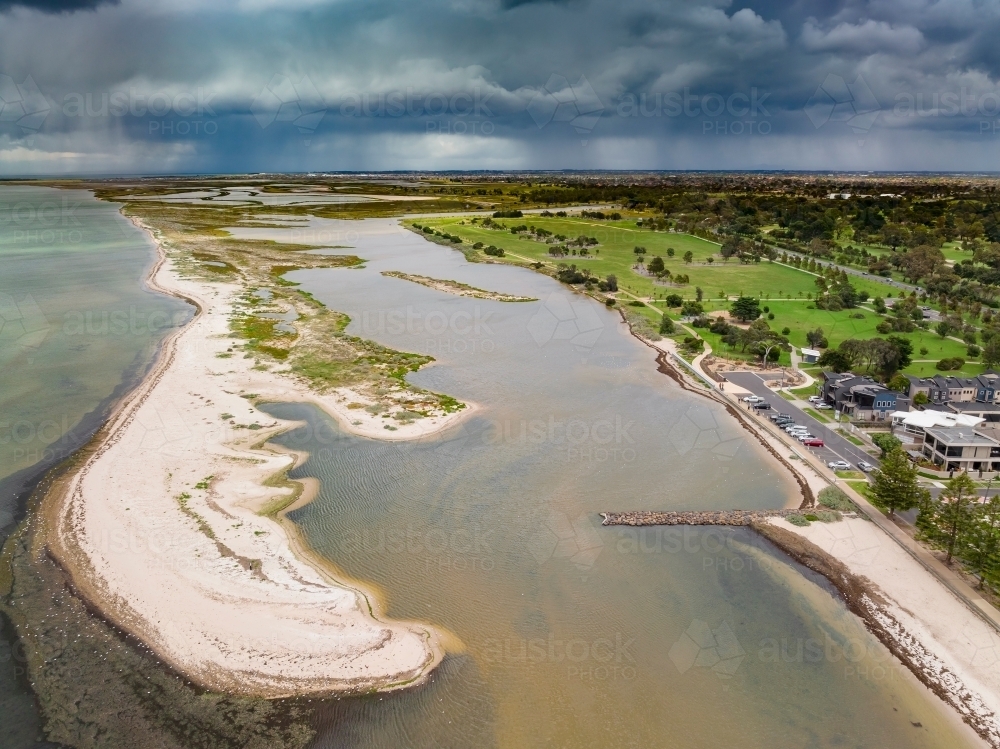 Aerial view of an unusually shaped sand bar running along the coast under dark rain clouds - Australian Stock Image