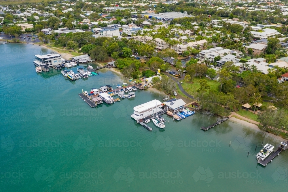 Aerial view of boats tied up at jettys along the river bank of a coastal town - Australian Stock Image