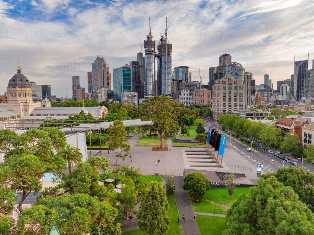 Aerial view of city park with paved forecourt and a city skyline behind, Carlton, Melbourne - Australian Stock Image