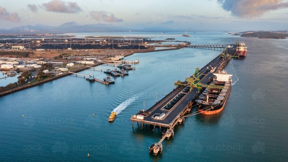 Aerial view of  coal ship and wharf with coal piles in the background - Australian Stock Image