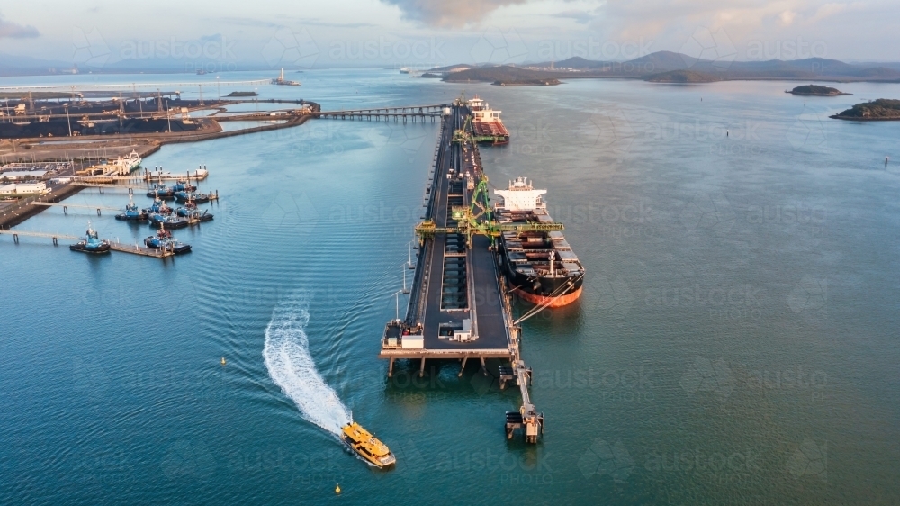 Aerial view of  coal ship and wharf with coal piles in the background - Australian Stock Image