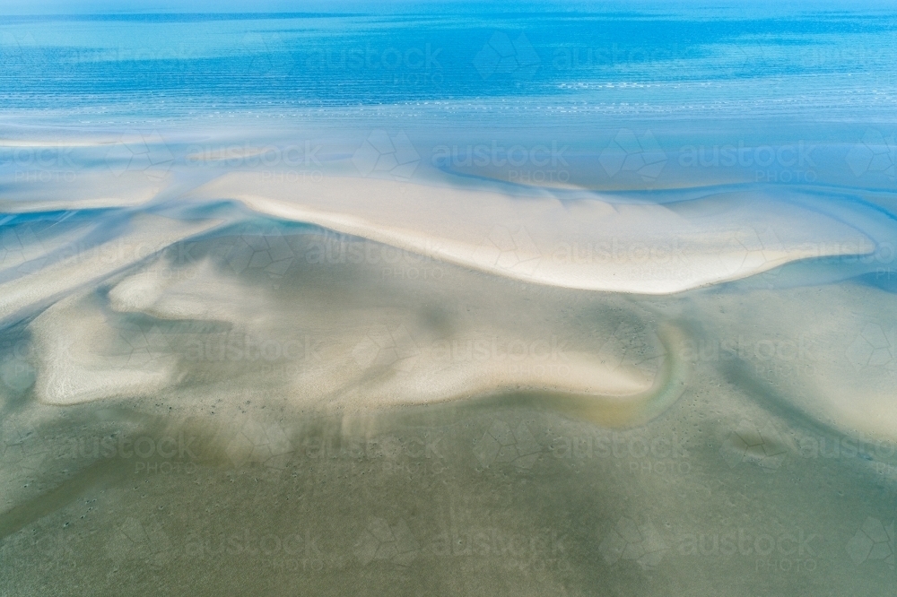 Aerial view of coastline and sandbar patterns in shallow blue water. - Australian Stock Image