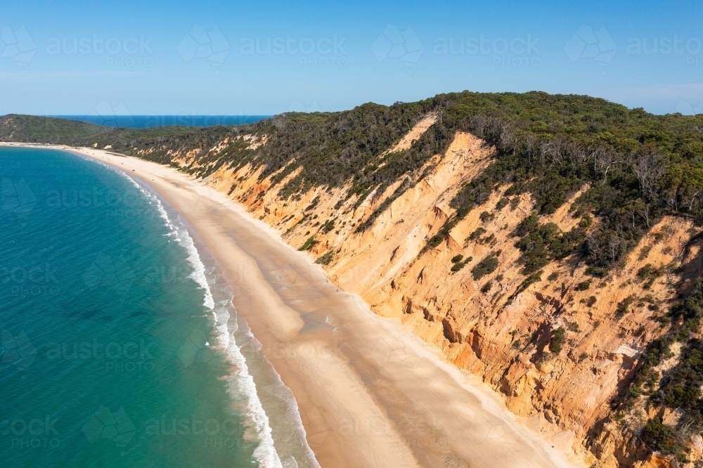 Aerial view of coloured sandy cliffs above a beach and blue ocean - Australian Stock Image