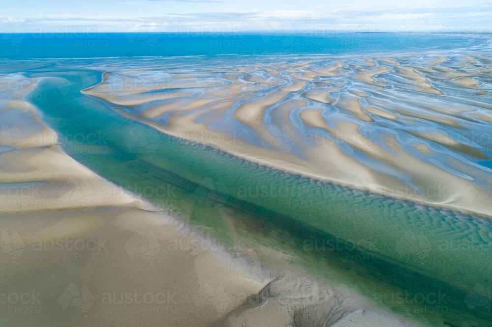 Aerial view of creek and sandbar patterns in shallow blue water. - Australian Stock Image