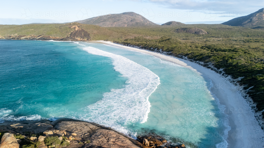 Aerial view of crescent-shaped beach with turquoise water. - Australian Stock Image