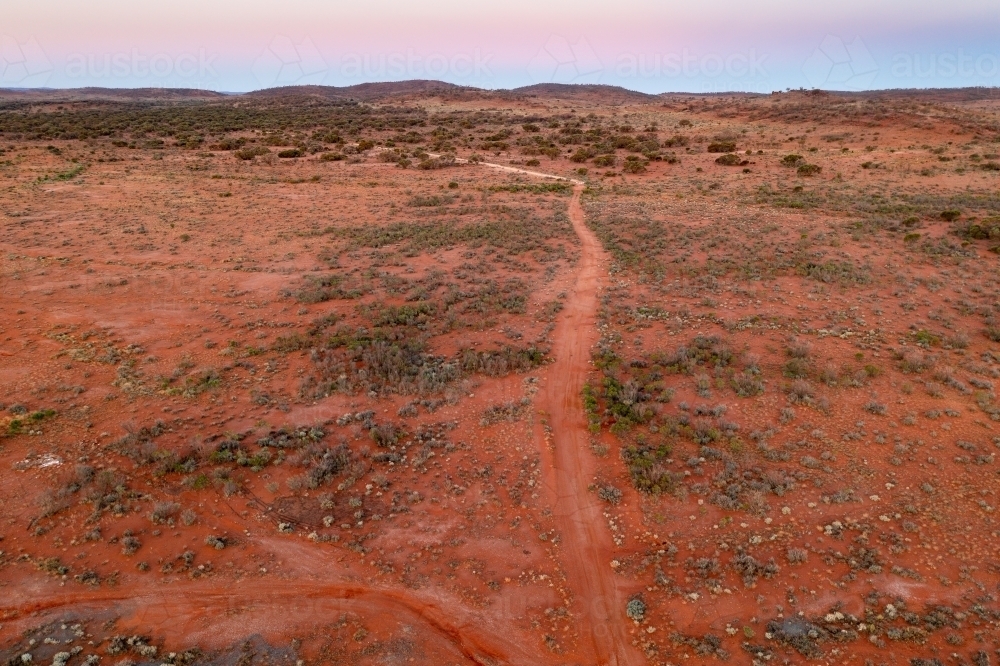 Aerial view of dirt tracks through a red outback landscape at twilight - Australian Stock Image