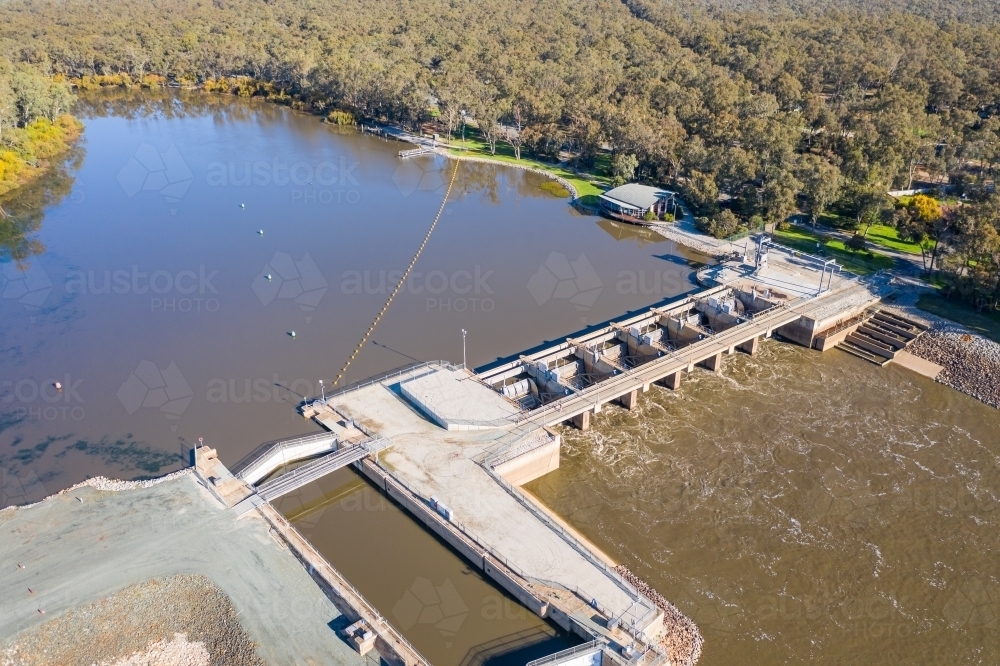 Aerial view of dirty river water rushing through the gates of a weir - Australian Stock Image