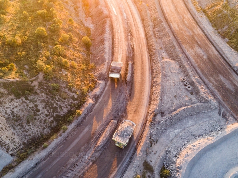 Aerial view of full and empty dump trucks passing one another in open cut mine site - Australian Stock Image