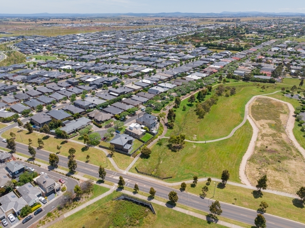 Aerial view of green parkland alongside a large outer suburban residential housing development - Australian Stock Image